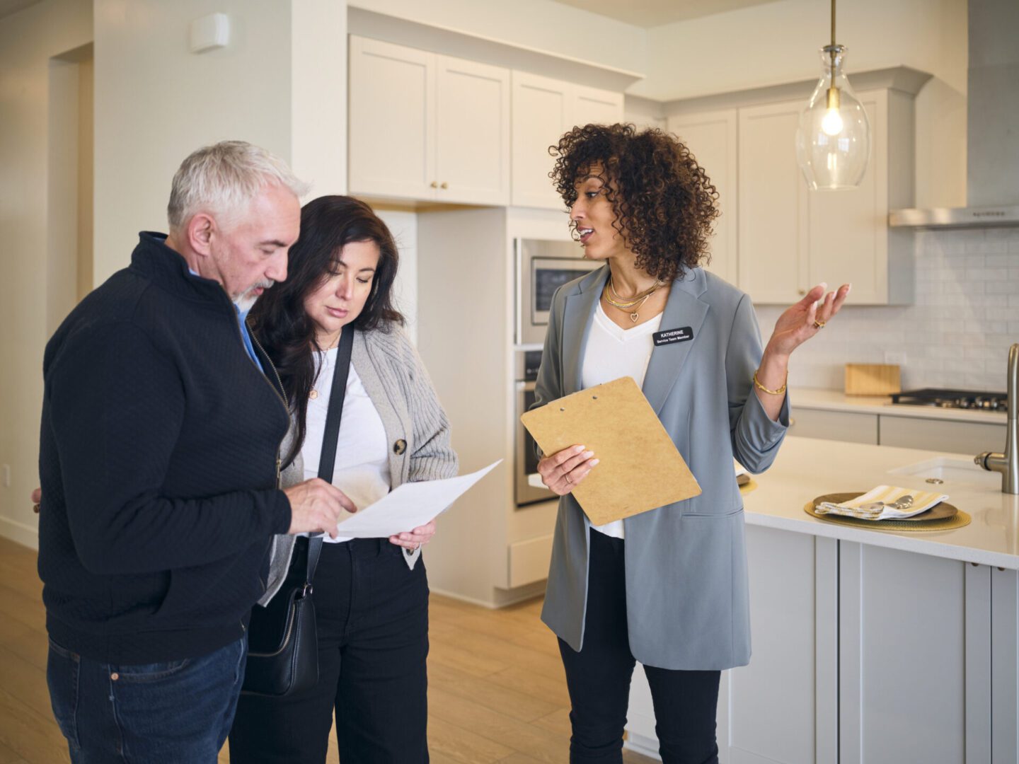 Realtor discussing with couple in modern kitchen.